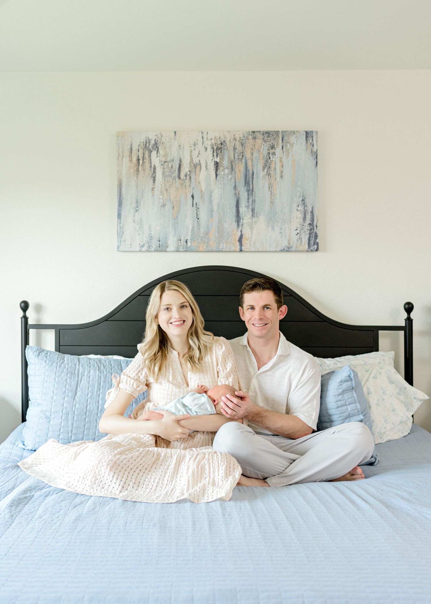 Family portrait on bed with abstract art and blue decor.