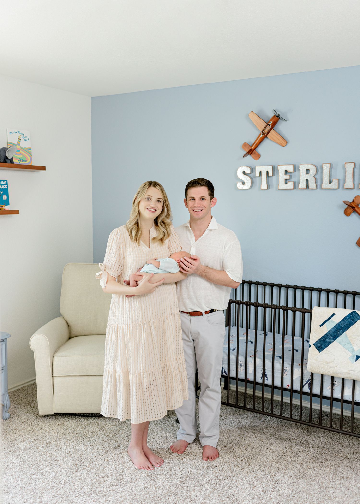 Modern nursery with aviation theme decor featuring blue walls and wooden airplane accents.