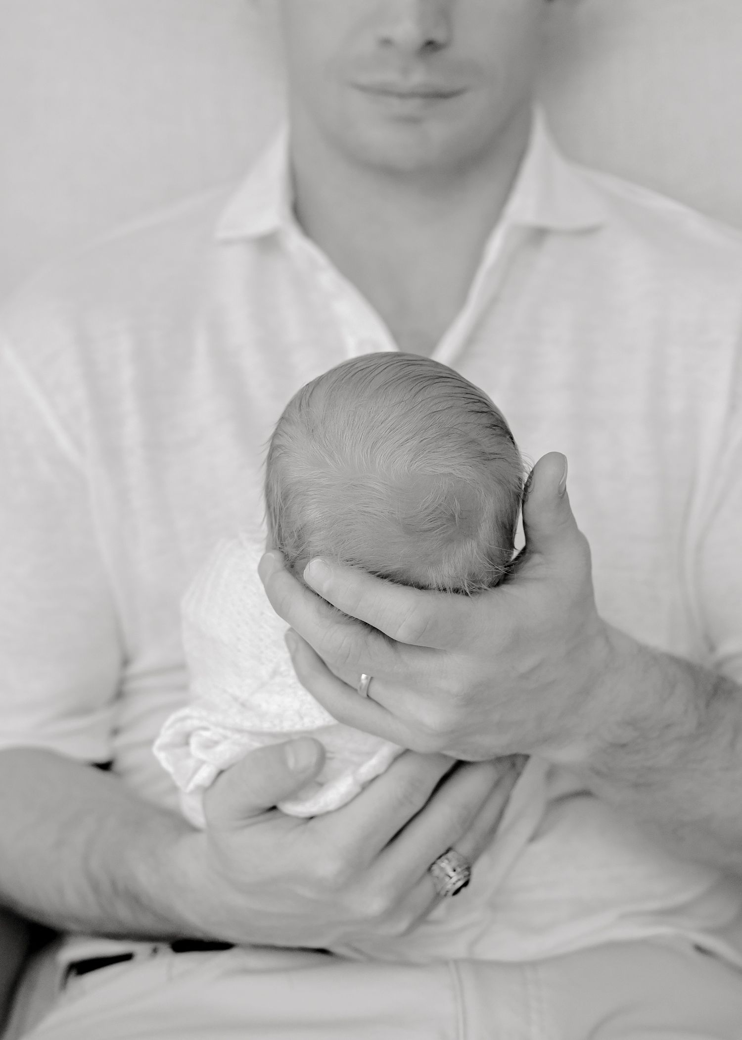 Close-up black and white photograph of hands tenderly cradling a newborn baby.