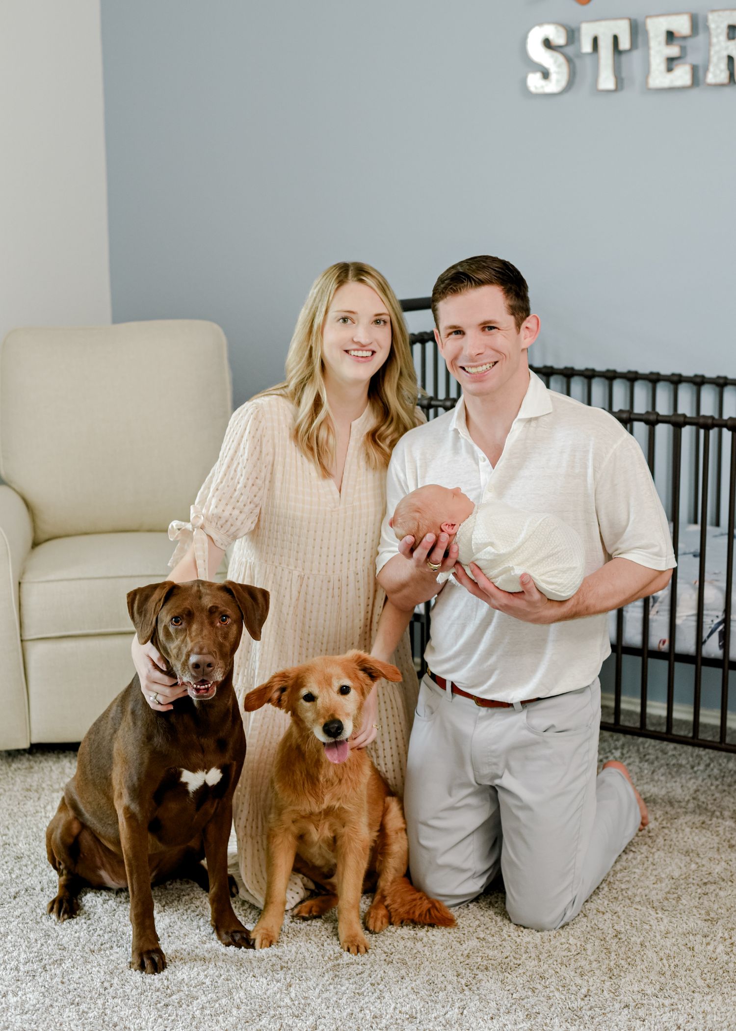 Family portrait in nursery with two dogs and baby in front of Sterling wall decor.
