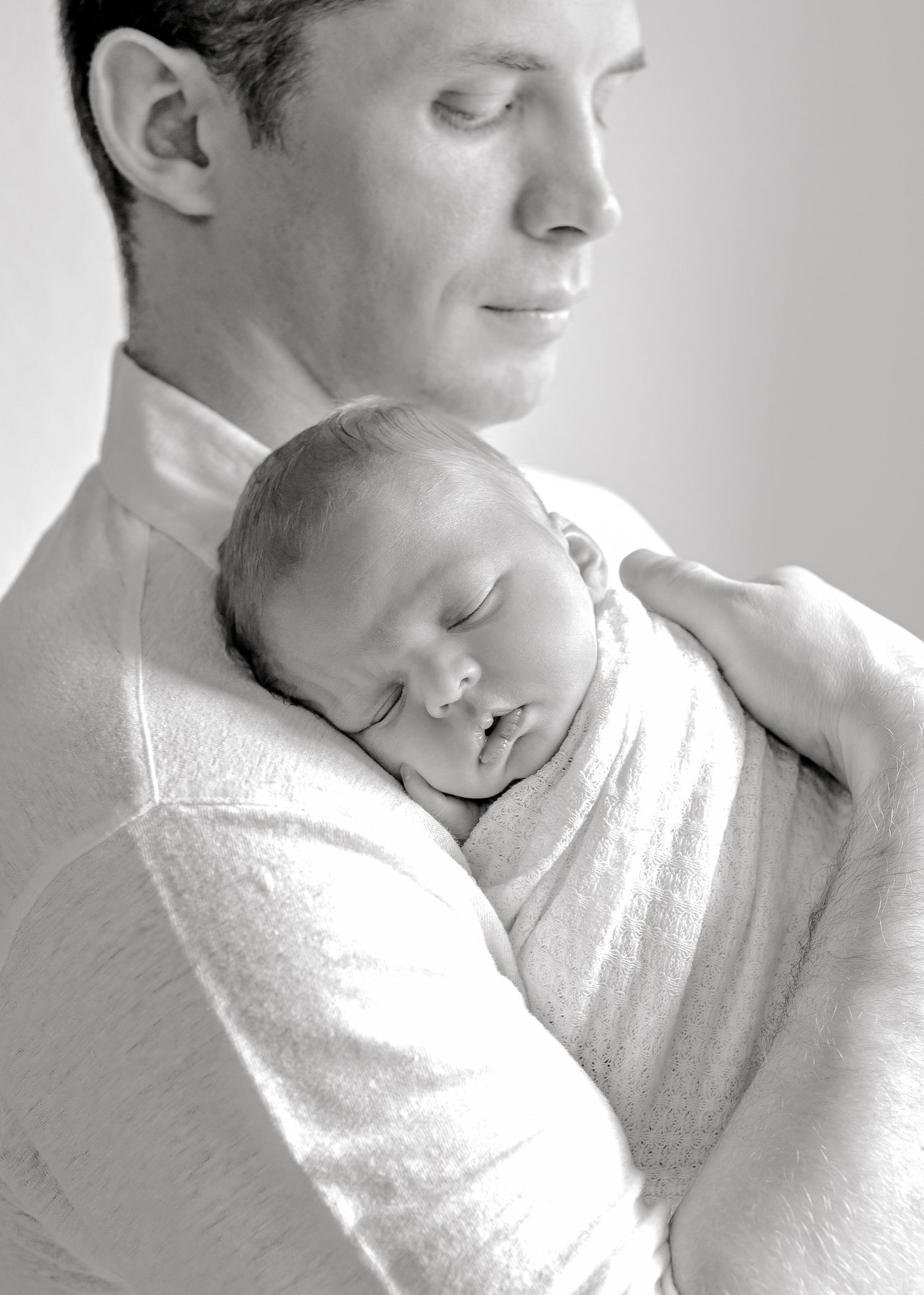 Black and white portrait of tender moment between parent and sleeping newborn.