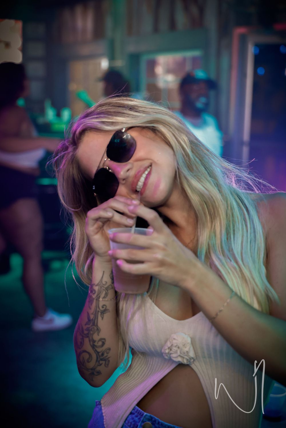 Person holding a camera to their face under vibrant nightclub lighting.