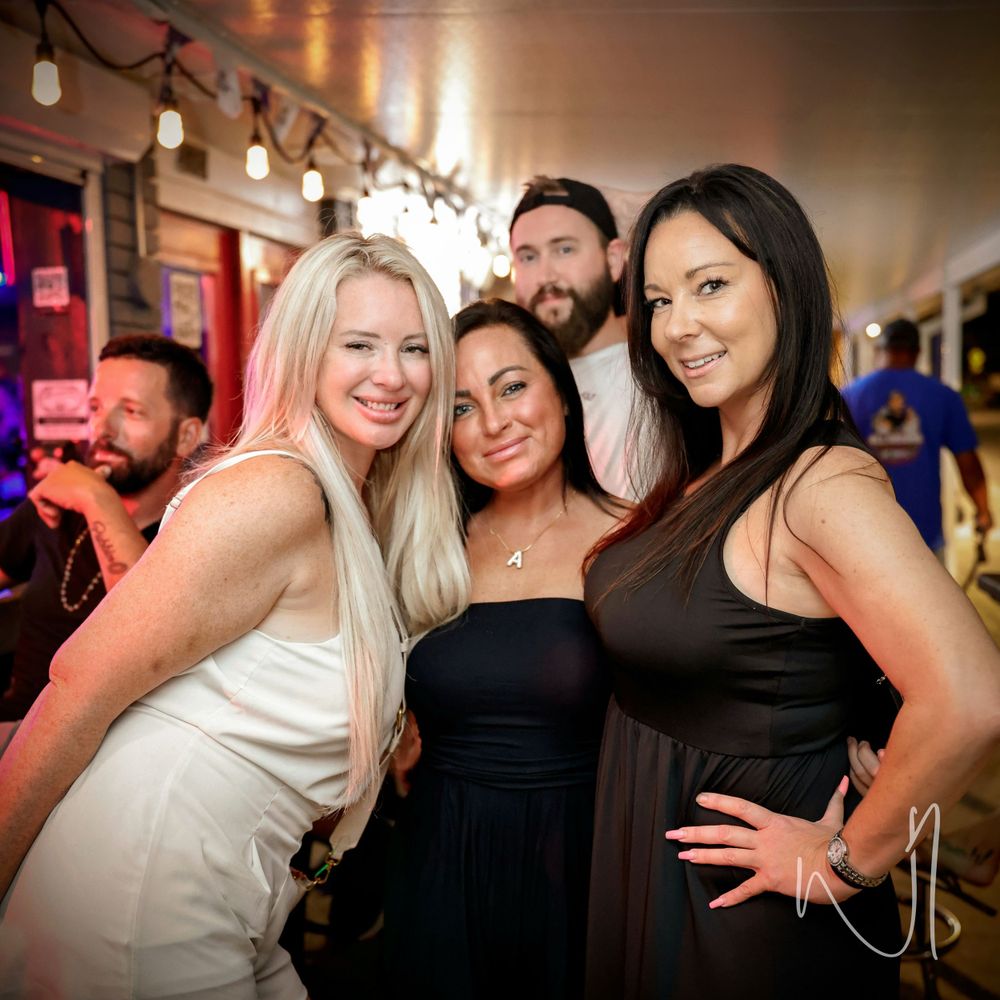 Group of friends posing together at a party under warm lighting.