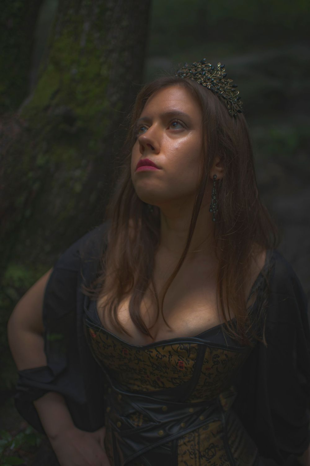 Dark fantasy portrait in forest featuring crowned figure in ornate corset dress.