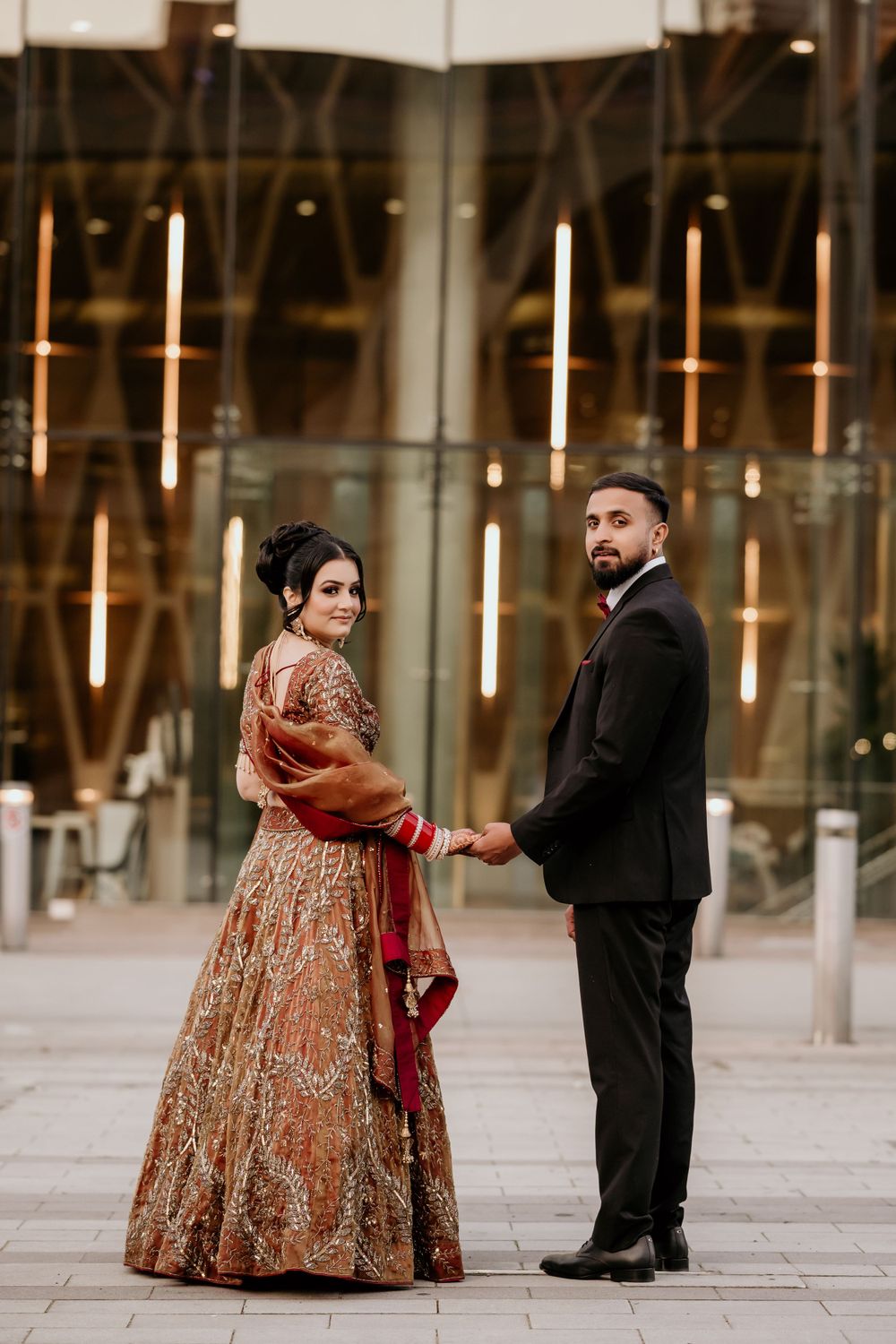 Romantic couple photoshoot with elegant formal attire in a modern architectural setting.