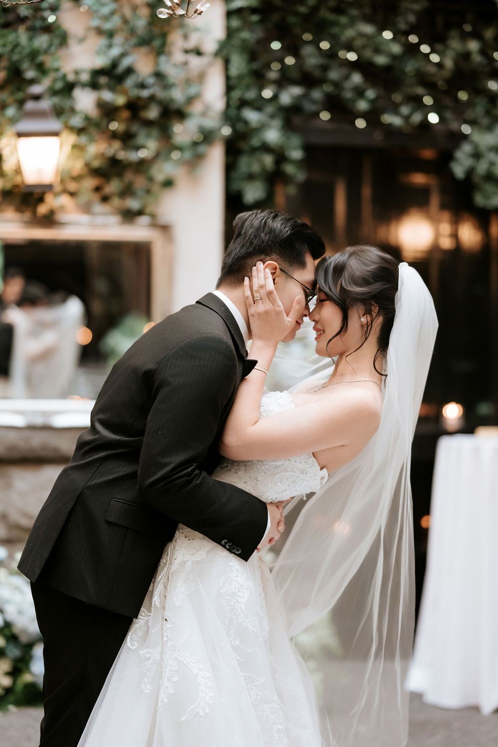 Romantic wedding couple sharing intimate moment under evening lights.