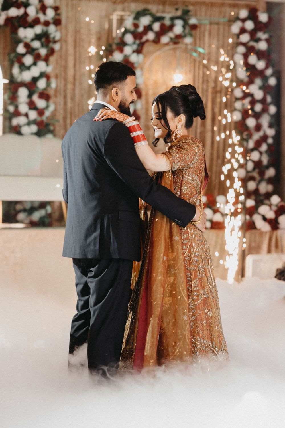 Wedding couple sharing an intimate moment under twinkling lights and floral decorations.