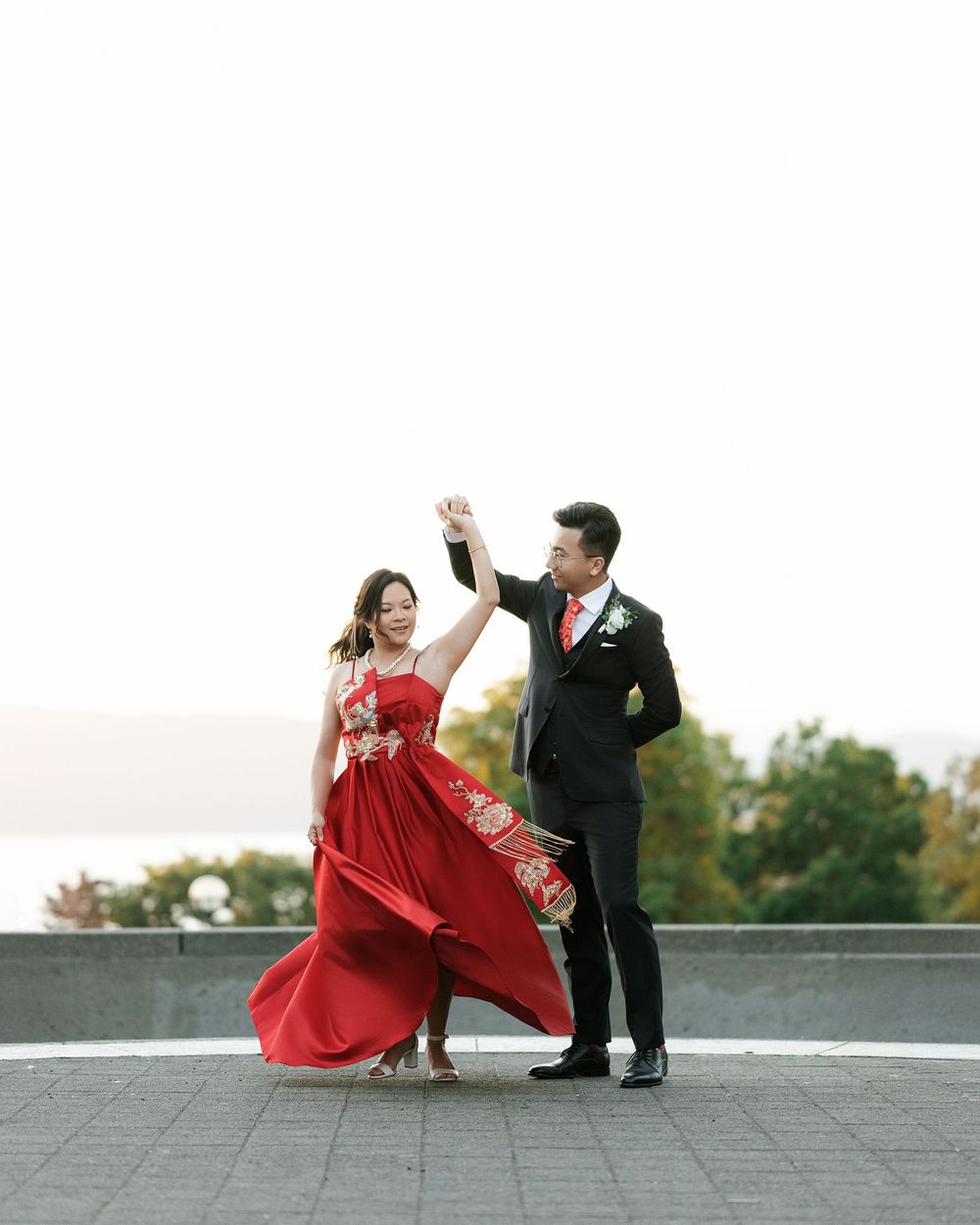 Couple in formal attire dancing on rooftop, red dress flowing in romantic sequence.