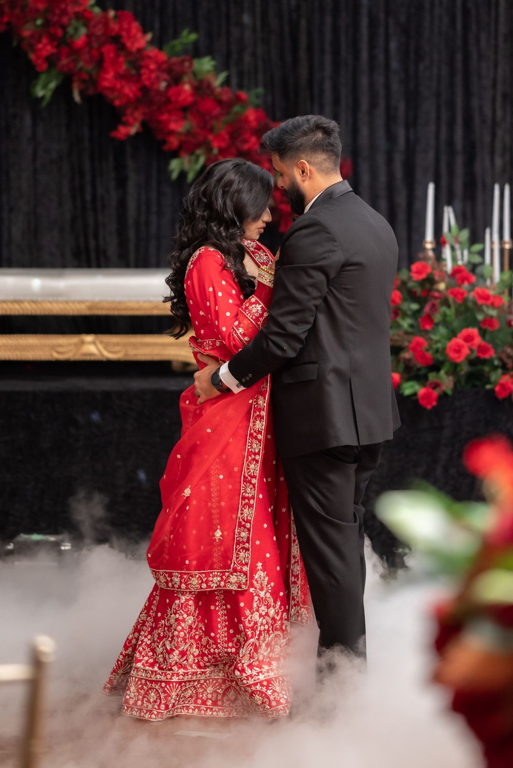 Wedding couple dancing surrounded by red roses and atmospheric fog effects.