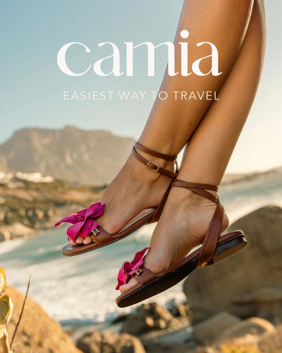 Sandals with pink bow detail shown against coastal mountain backdrop with Camia branding.