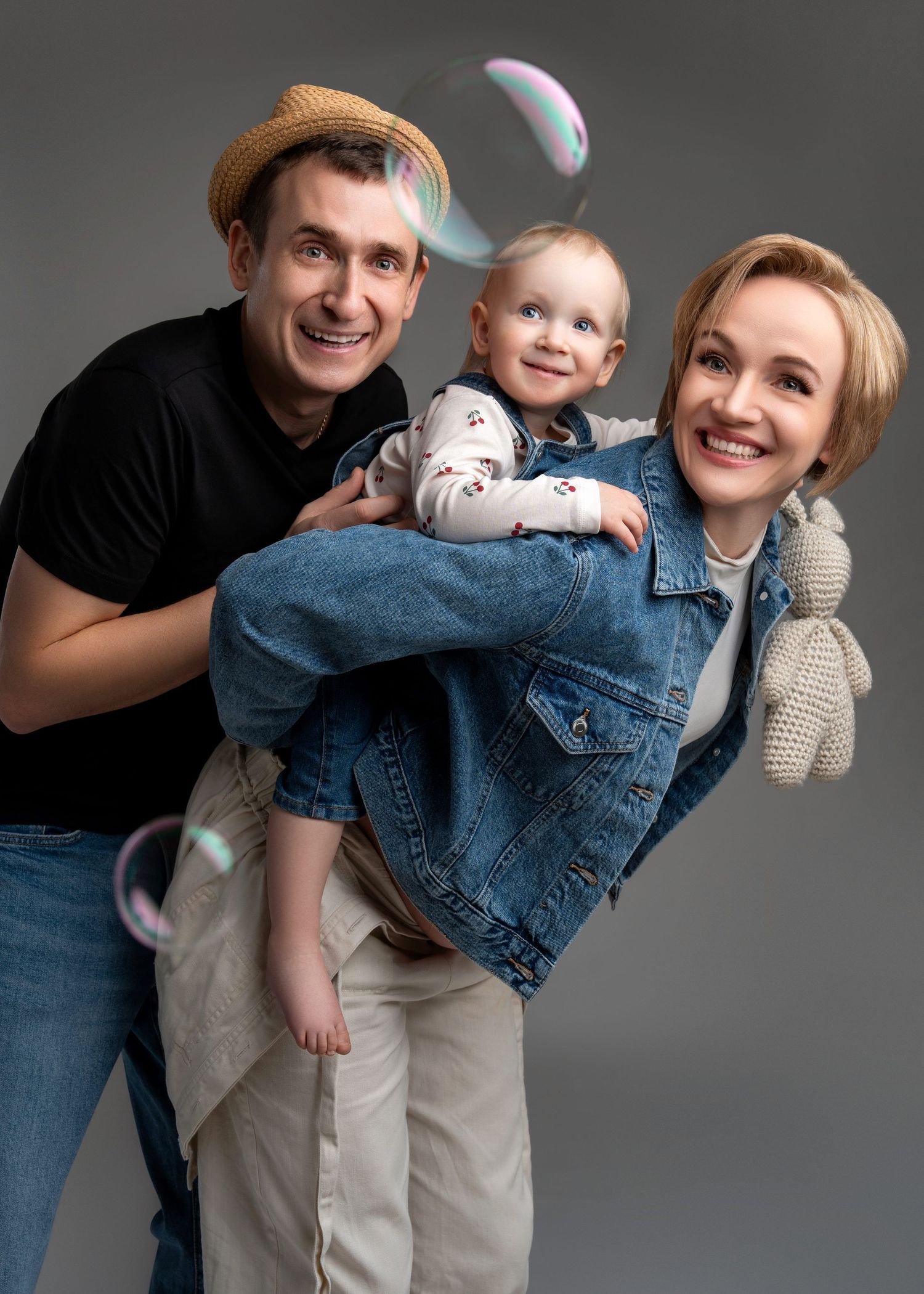 maternity photo shoot in studio featuring a family of three with one on the way standing together with bubbles floating