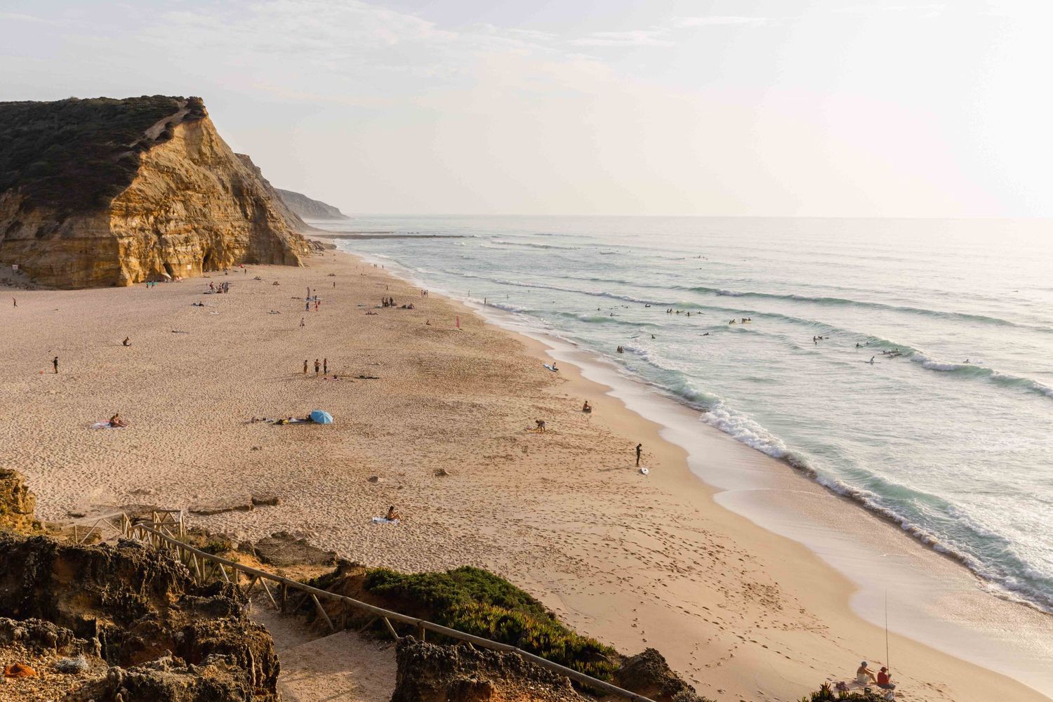 Scenic beach with tall cliffs and waves rolling onto sandy shore.
