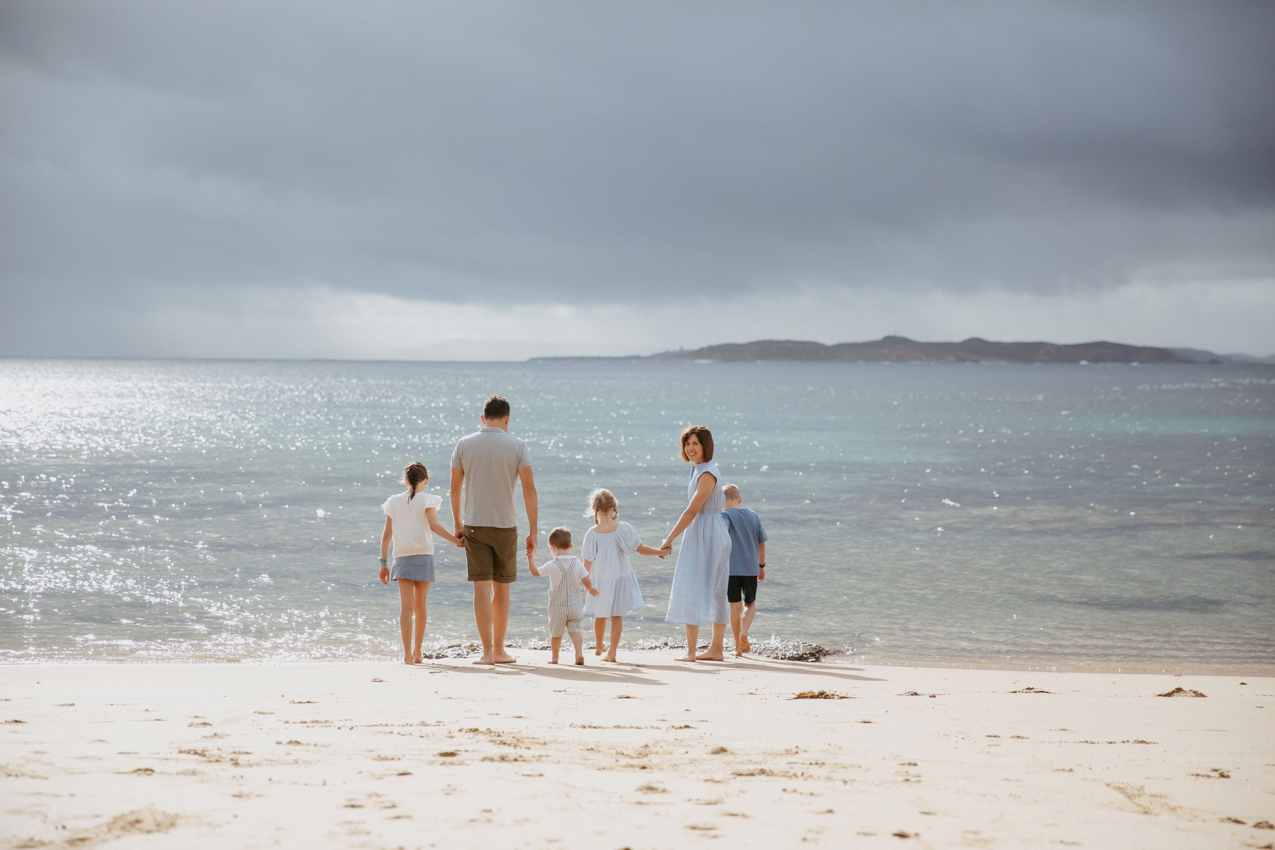 Family holding hands having fun on the beach in Point Lonsdale