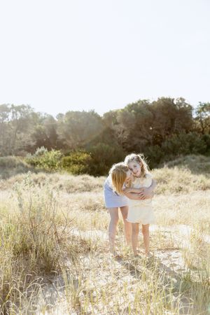 A couple shares an intimate moment in a sun-drenched field of tall grass and wildflowers during golden hour.
