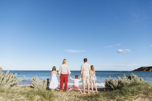 A group stands together on a grassy coastal overlook with ocean views on a sunny summer day.