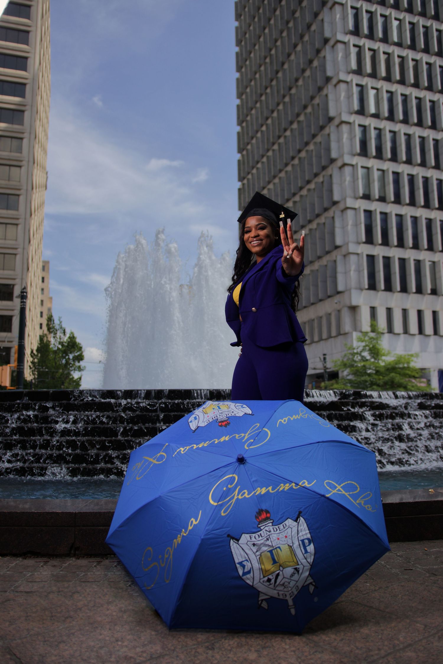 Joyful graduate celebrating near the fountain on campus during golden hour