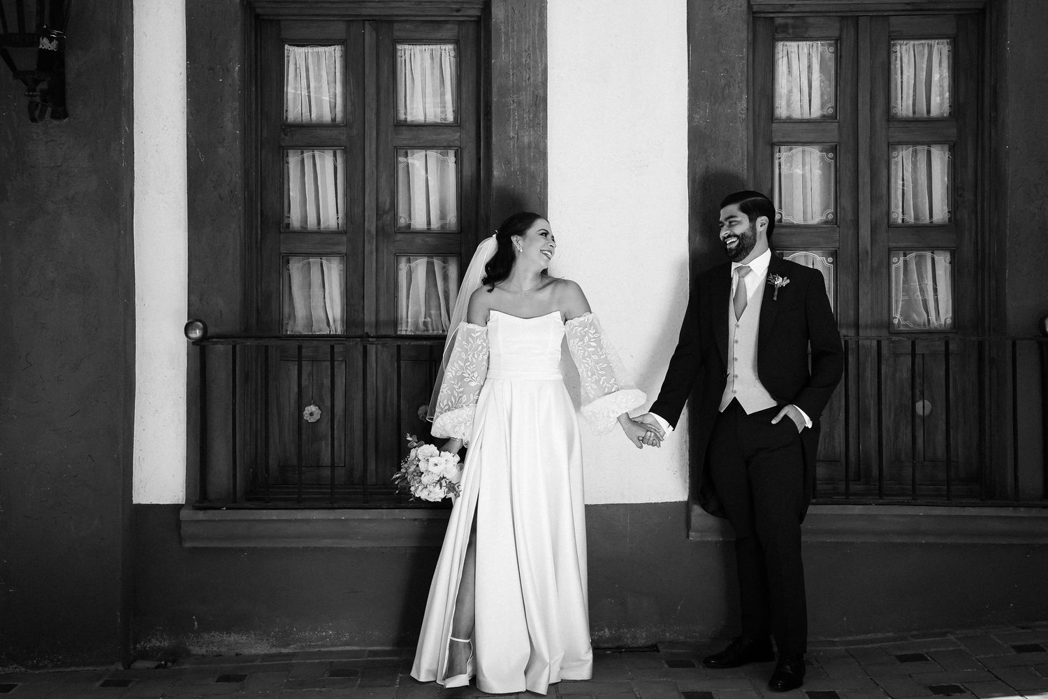 Black and white wedding photo of a couple posing elegantly against historic doors.