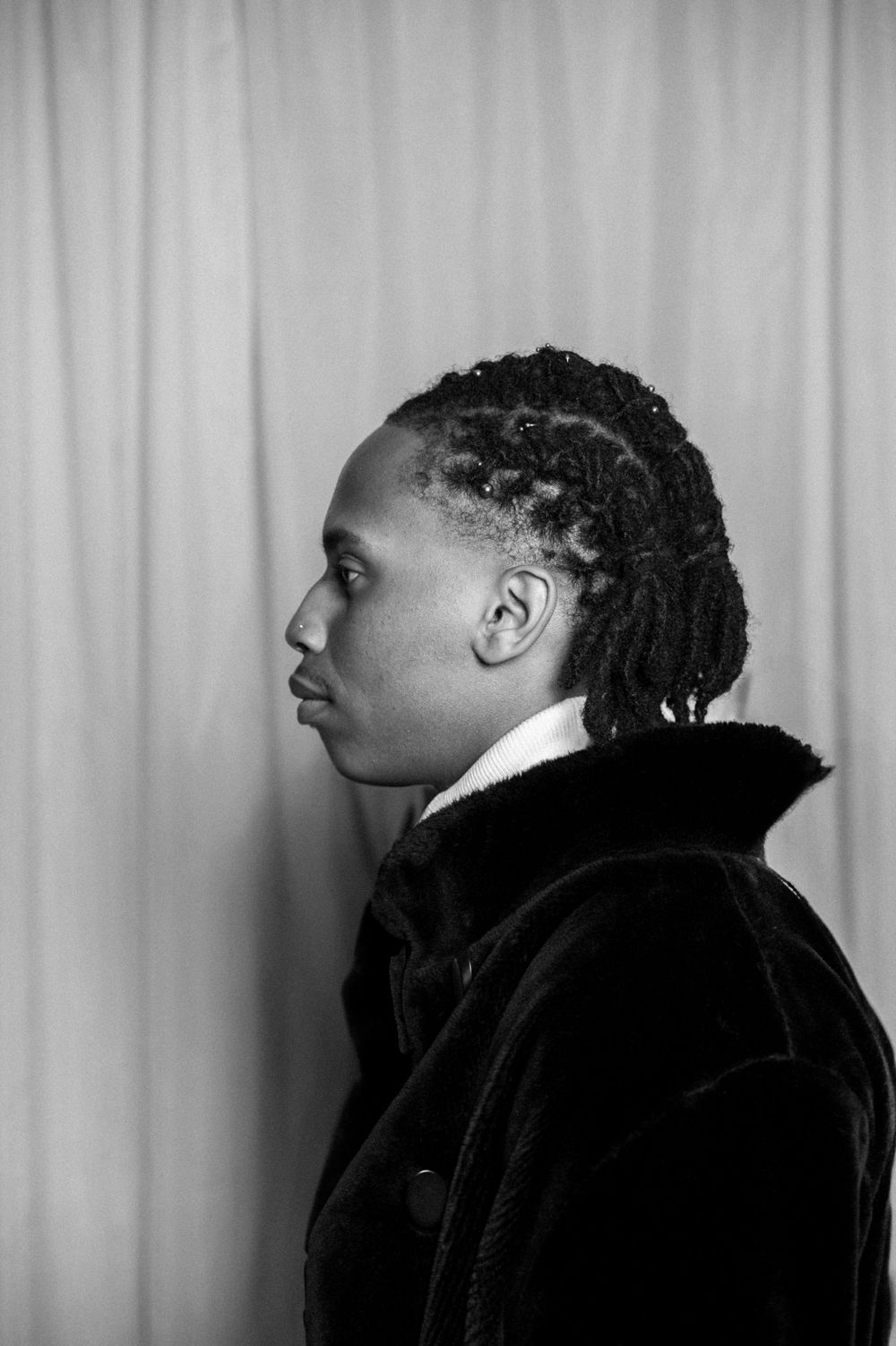 Professional black and white portrait photo showing a side profile in stylish dark clothing.