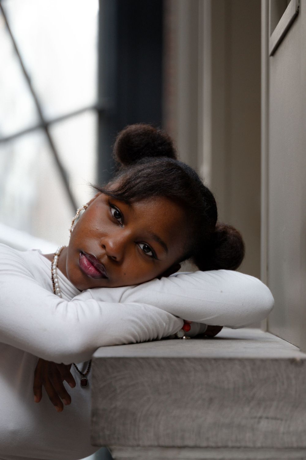 Intimate portrait by a window showing soft natural lighting and gentle expression.
