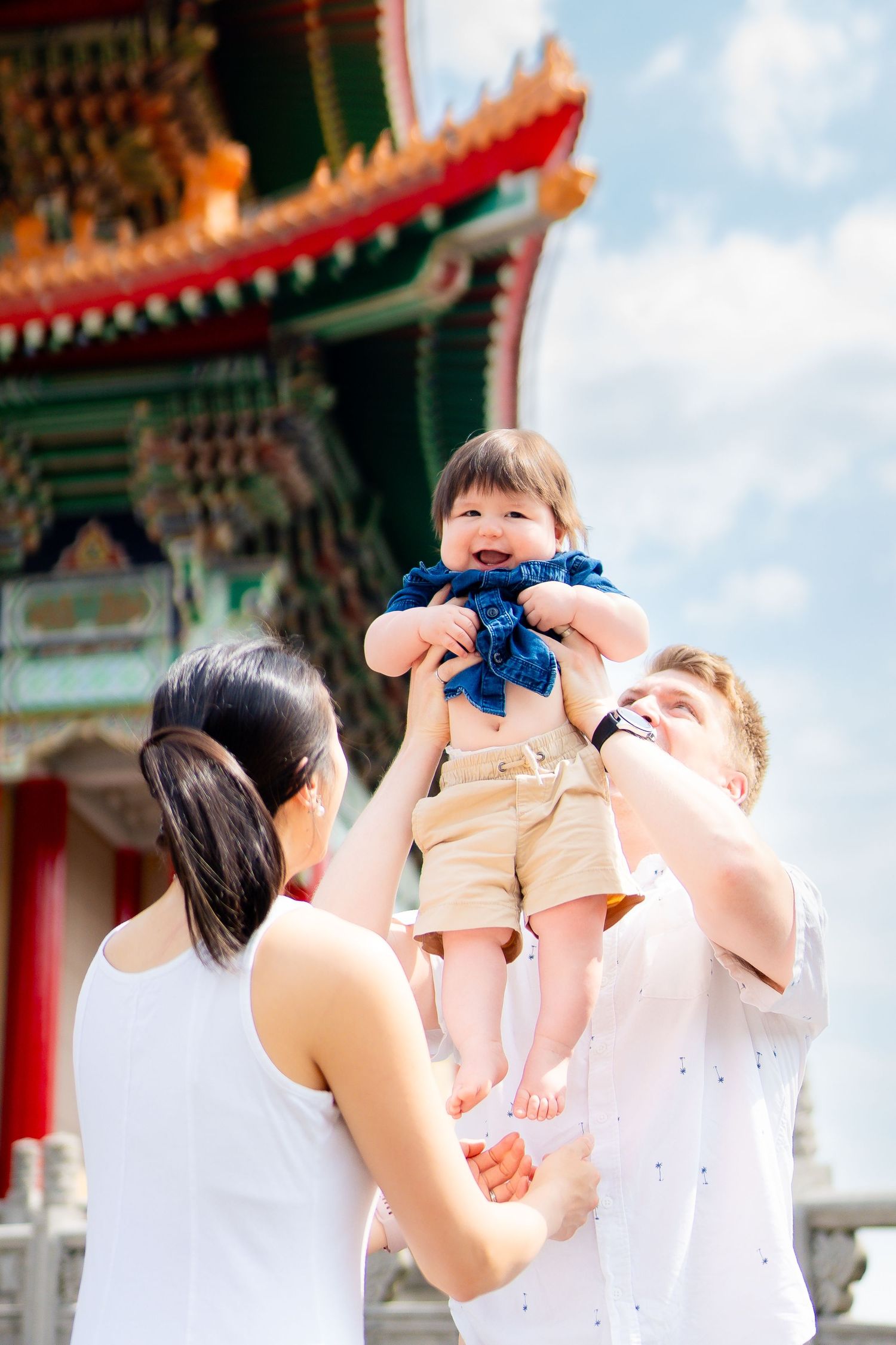 A joyful moment in front of a traditional Chinese temple with ornate red and gold architecture.