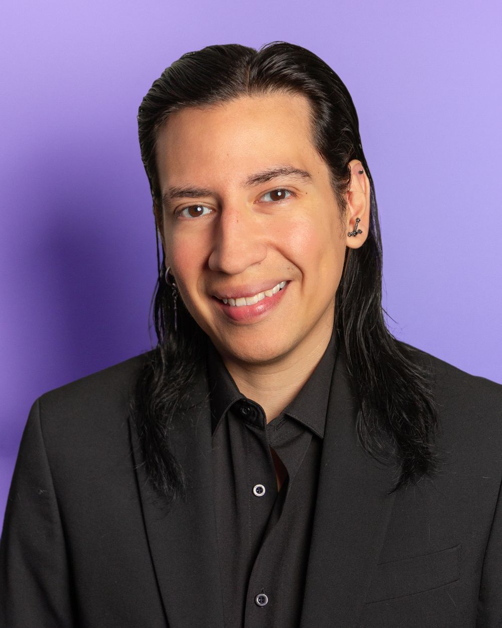 Professional headshot against purple background wearing black suit.