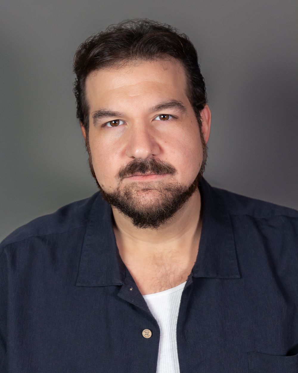 Professional headshot in navy shirt against grey background.