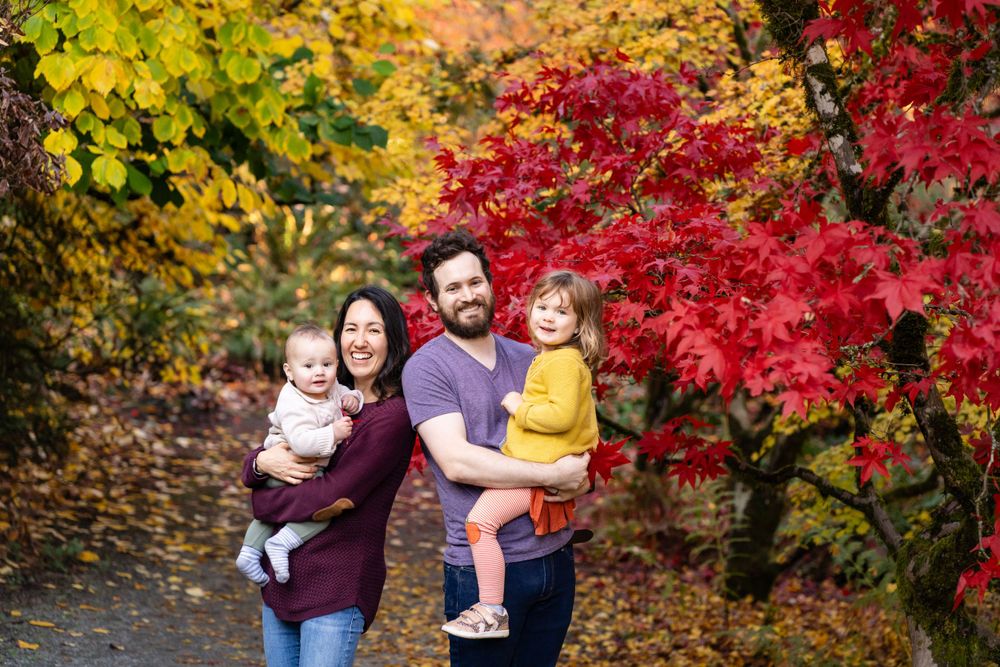Family smiles in front of Japanese maples in Seattle.