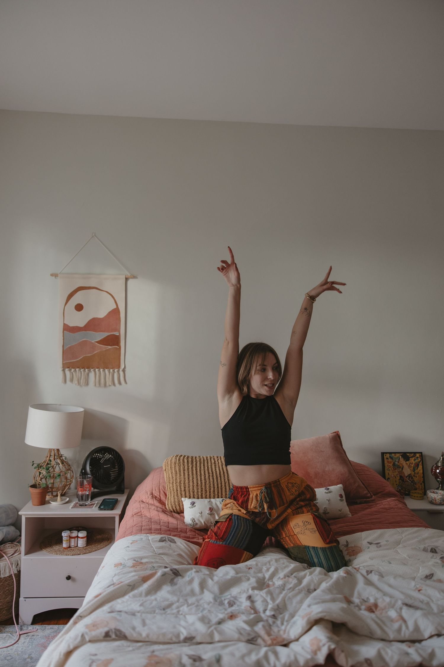 A sequence of photos showing someone stretching and moving playfully on a cozy bed with pink wall art and white bedding.