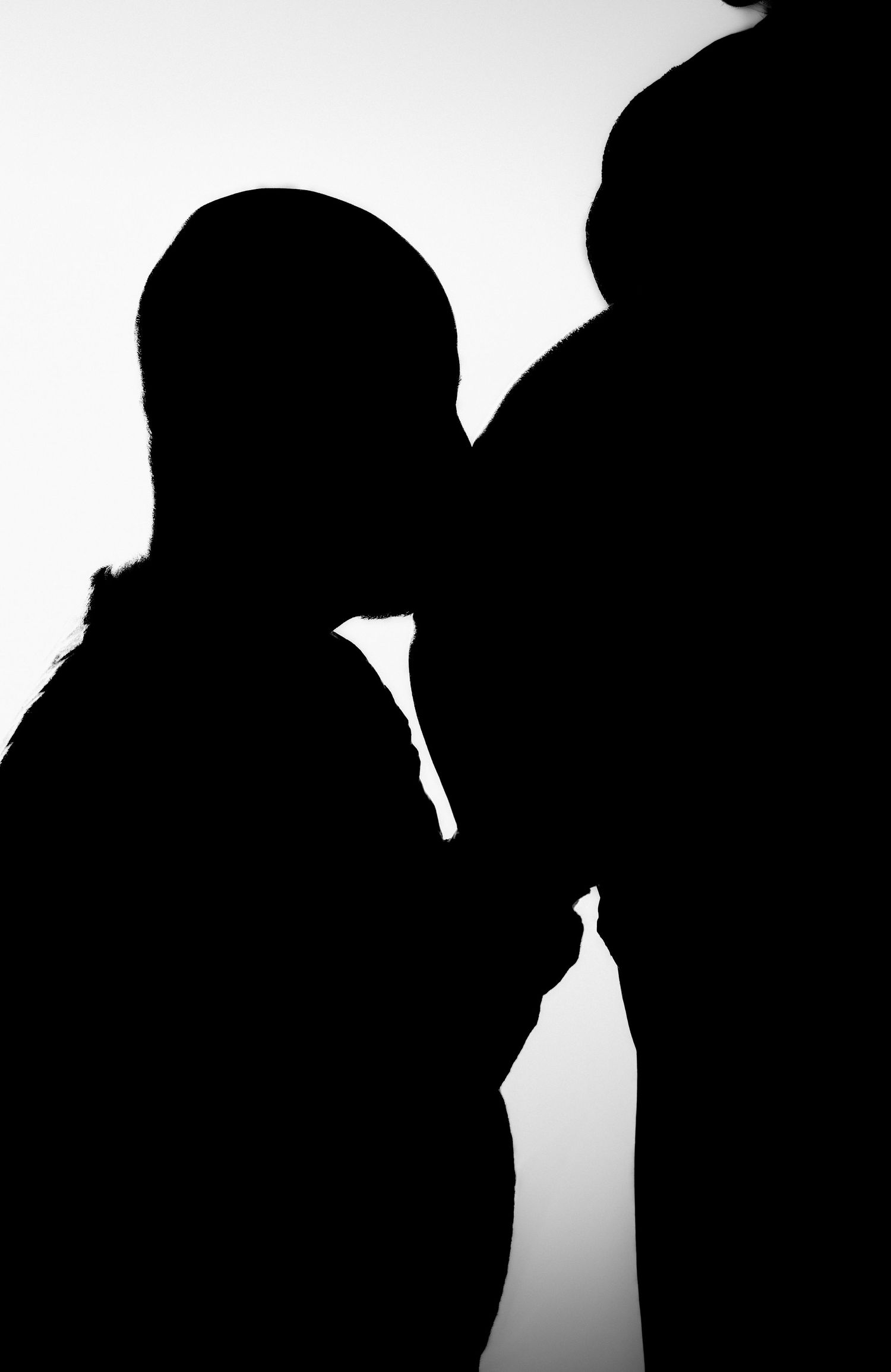 Shadow of a father kissing the mother’s belly in a black-and-white maternity photoshoot in Ange-Gardiens, Quebec.