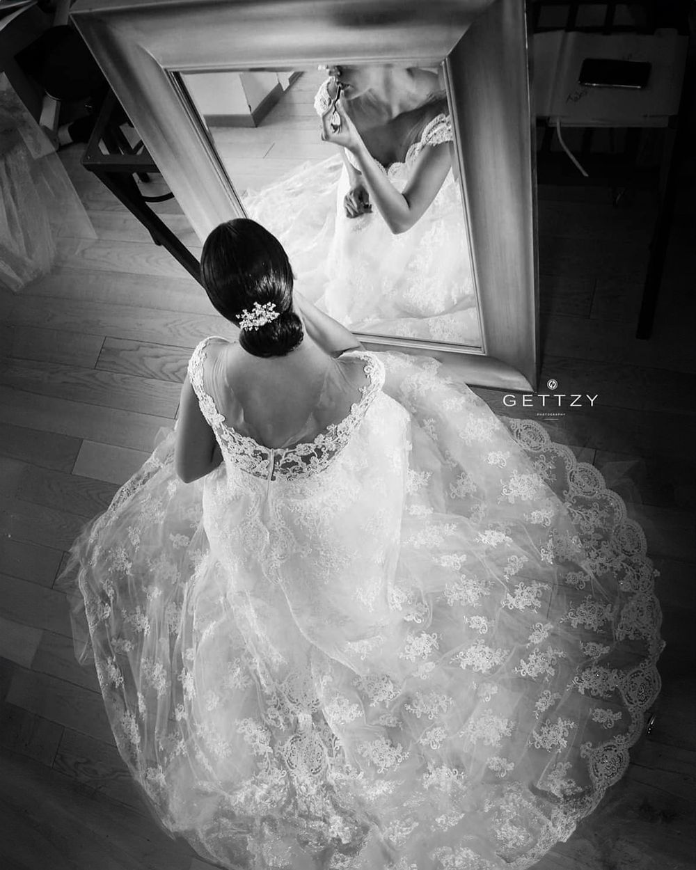 Overhead view of bride in flowing lace gown looking in mirror with elegant updo hairstyle in Zagreb