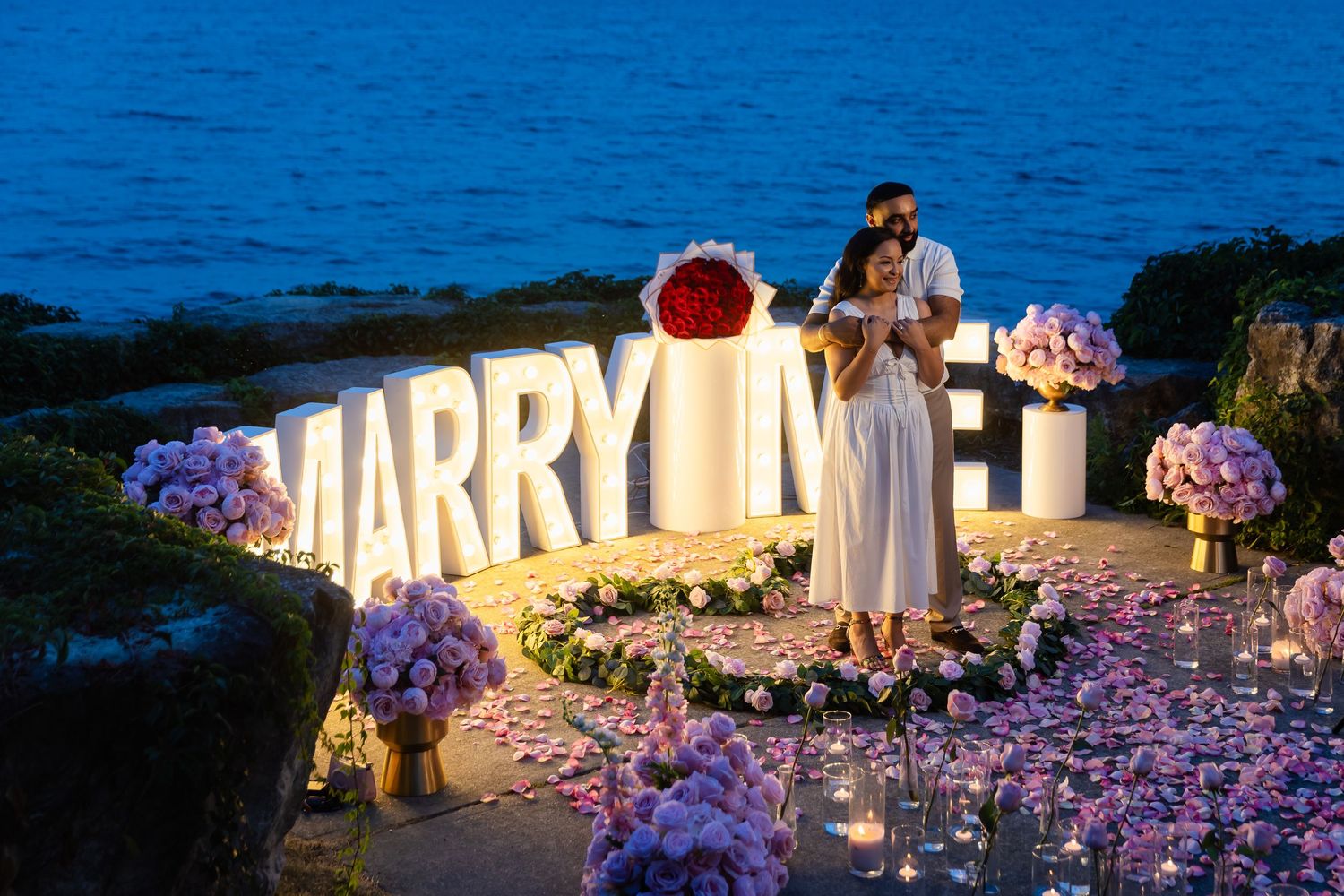 A joyful couple laughs together in an elegant evening setting with city lights visible through windows.