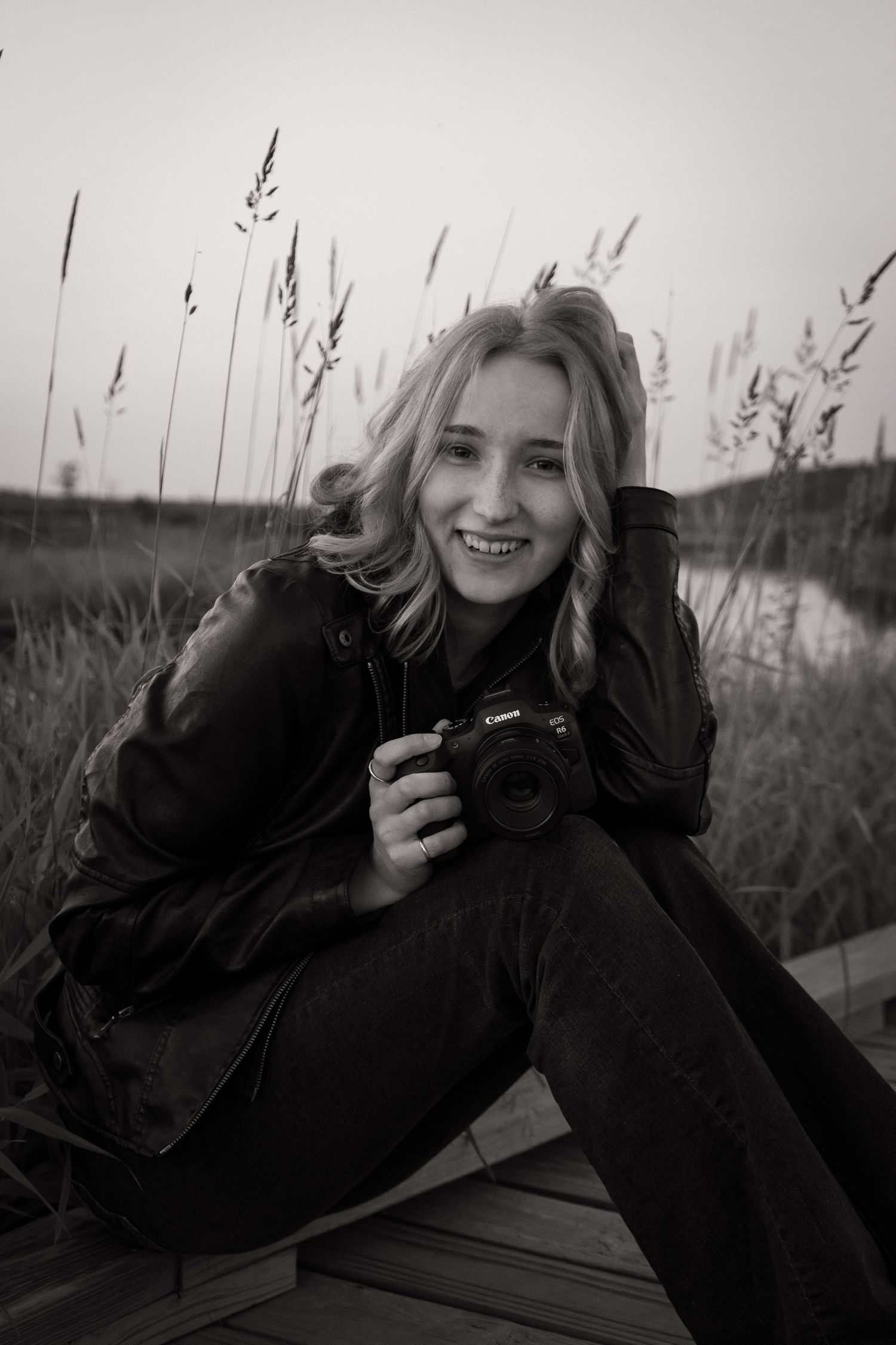 Black and white portrait of photographer with camera in outdoor setting.