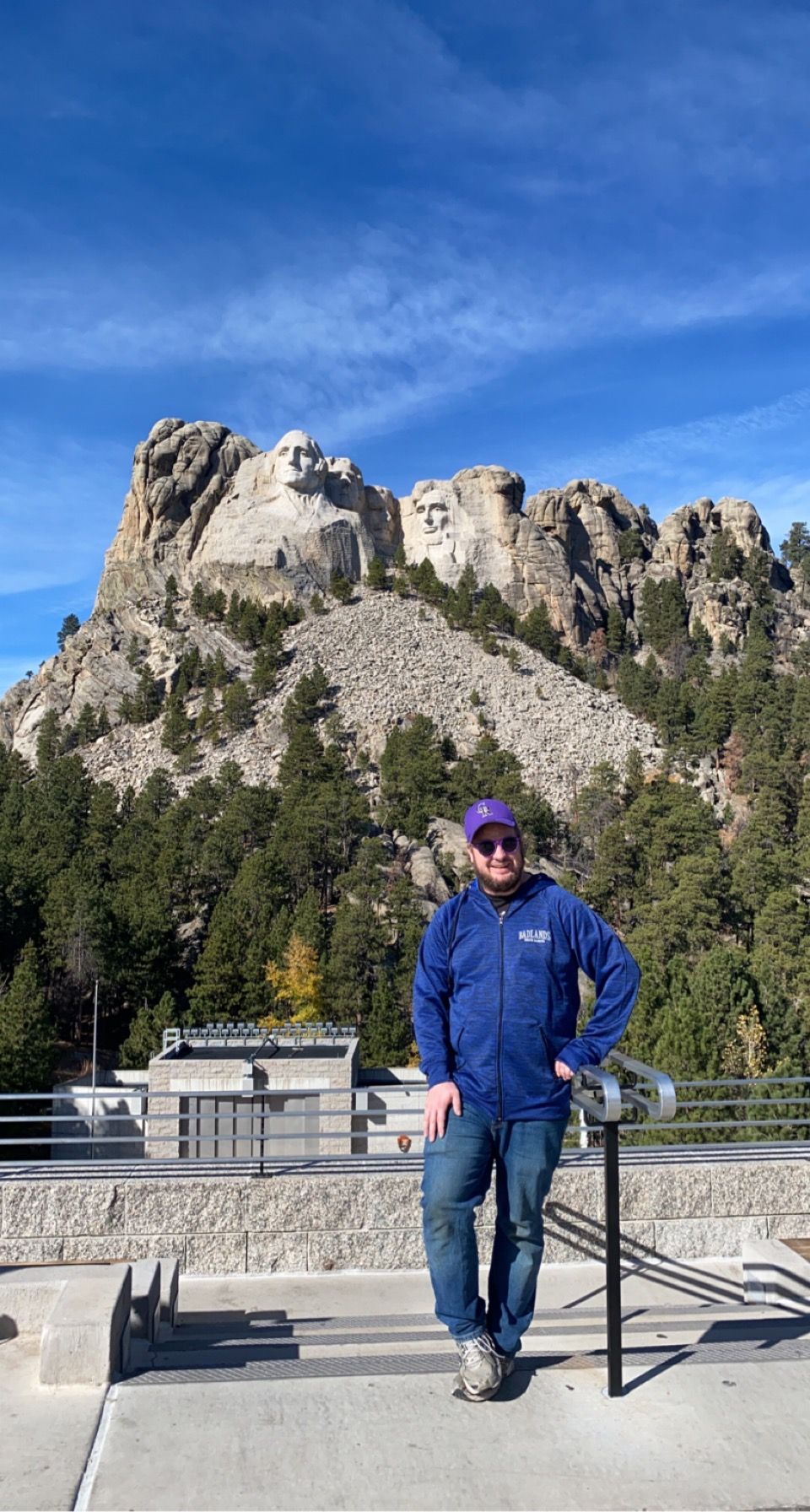 Tourist visiting Mount Rushmore standing at the memorial's viewing platform on sunny day.