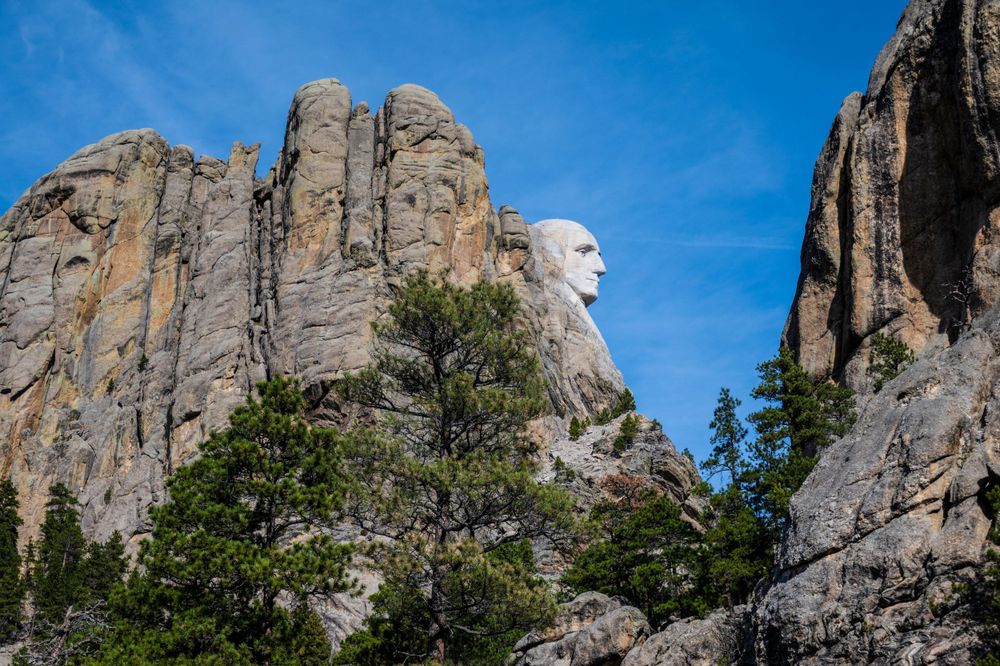 Profile view of Mount Rushmore showing the carved granite faces emerging from rugged rock formations.