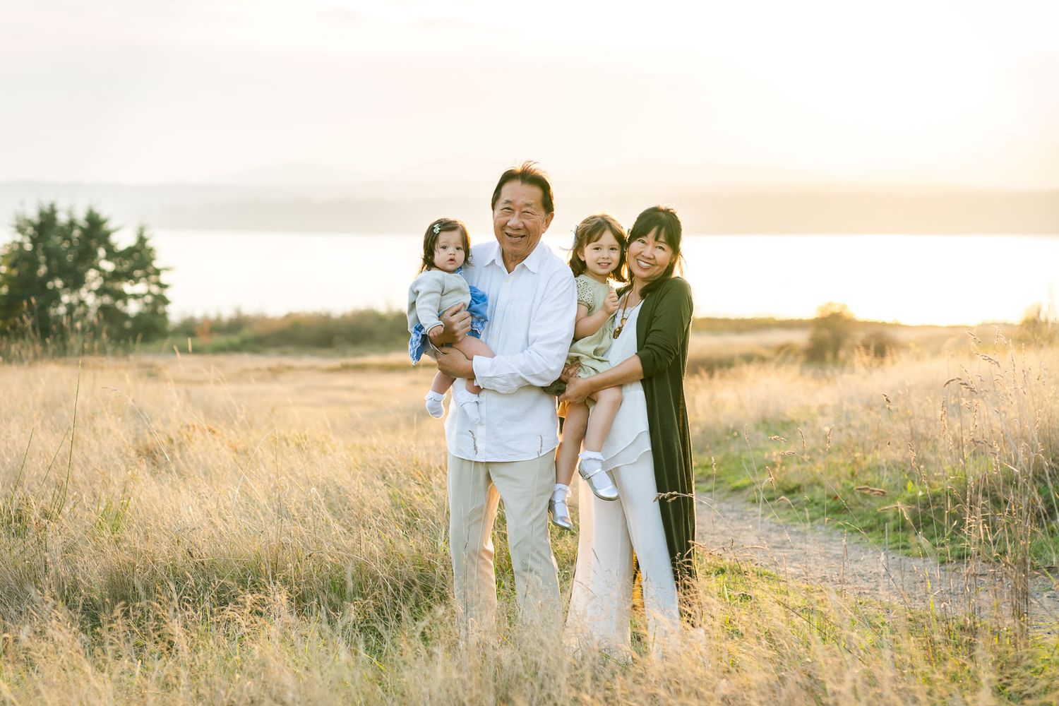 Grandparents hold their grandchildren for a portrait at Discovery Park in Seattle at sunset.