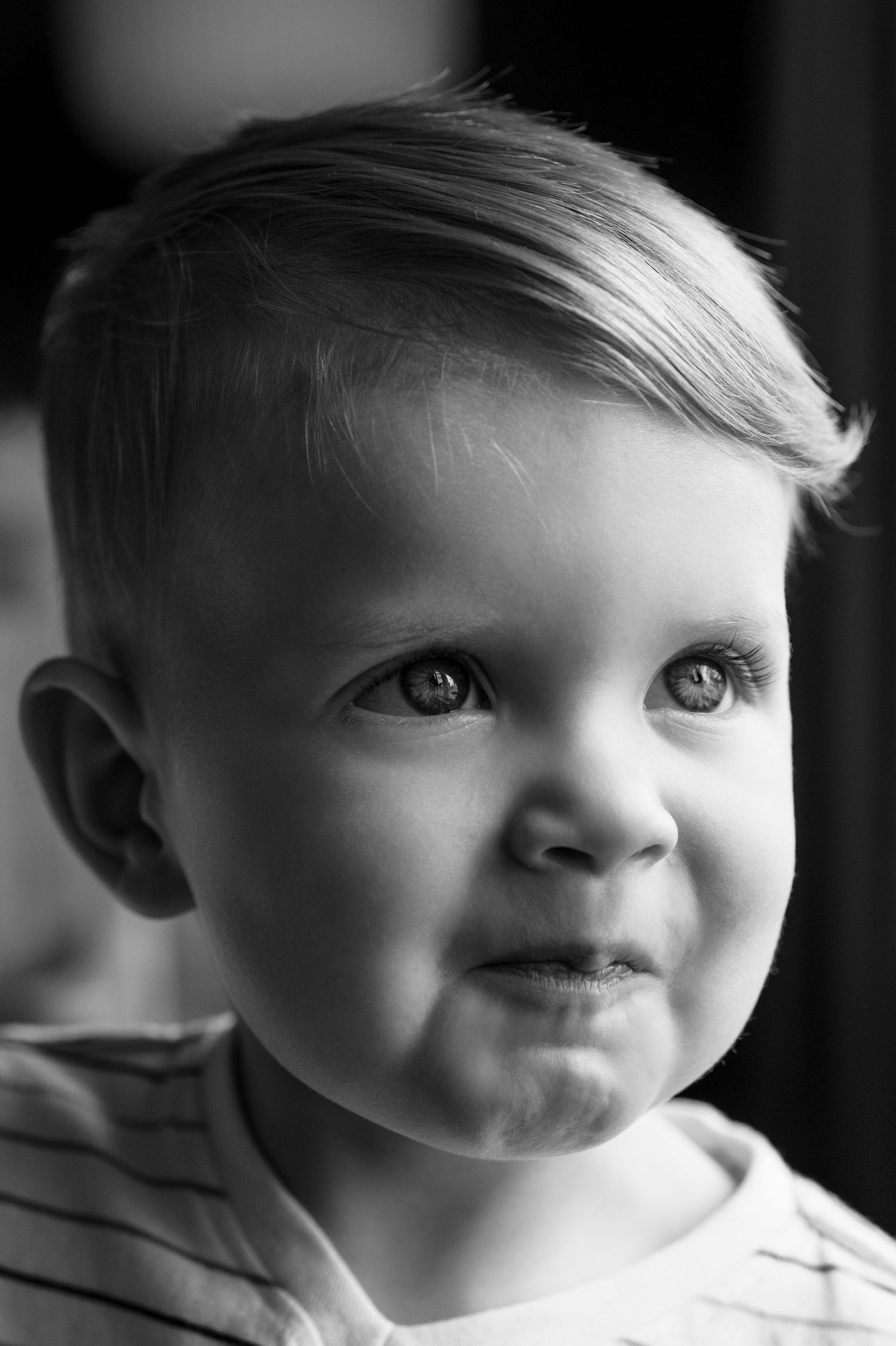 Black and white portrait of a young child with a sweet smile and bright eyes looking off to the side.