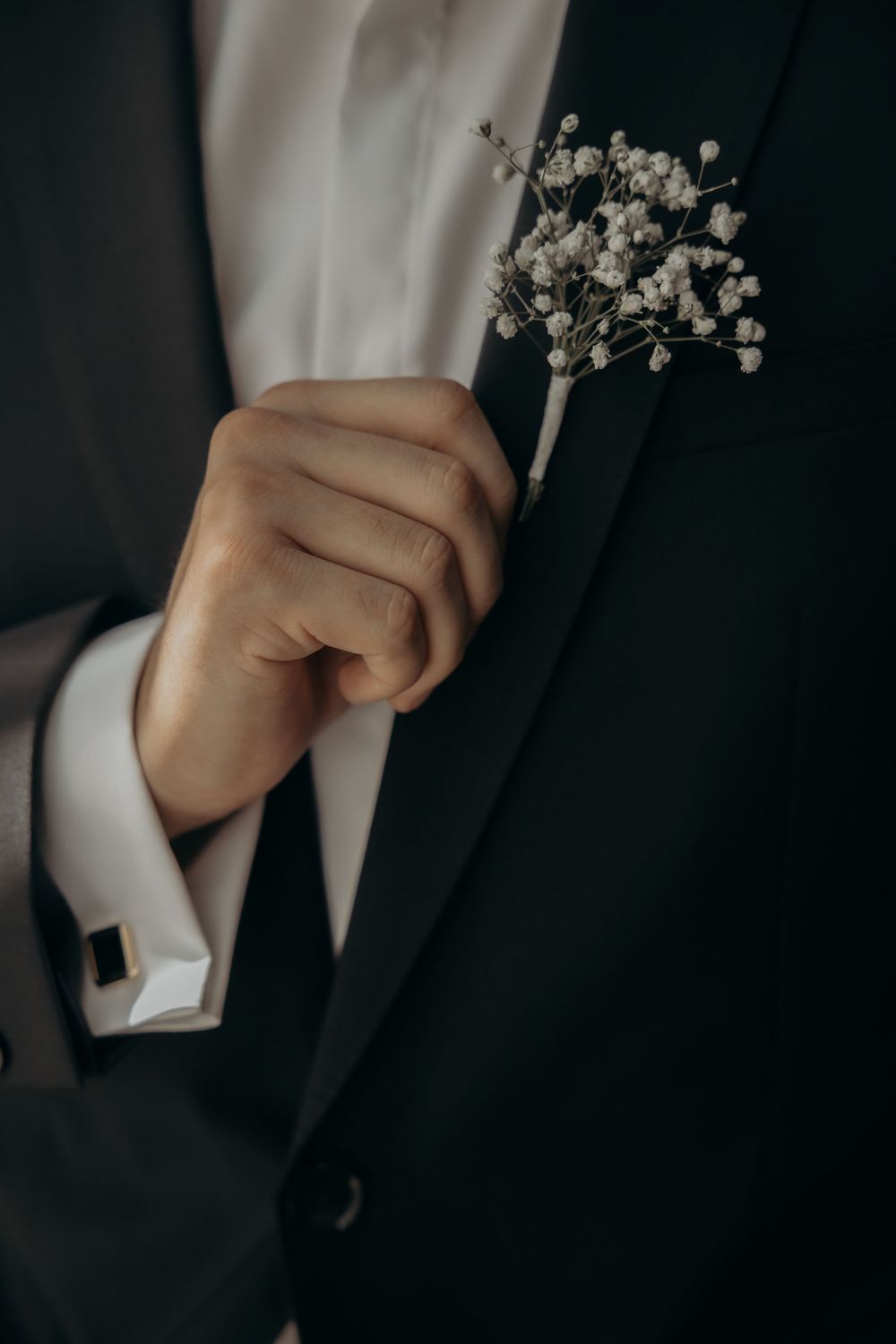 white boutonnières worn by a groom to accessorize his tuxedo look