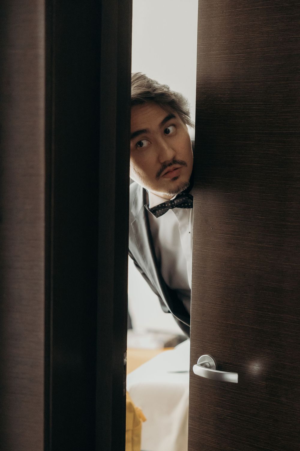Man in wedding suit peeking through the door