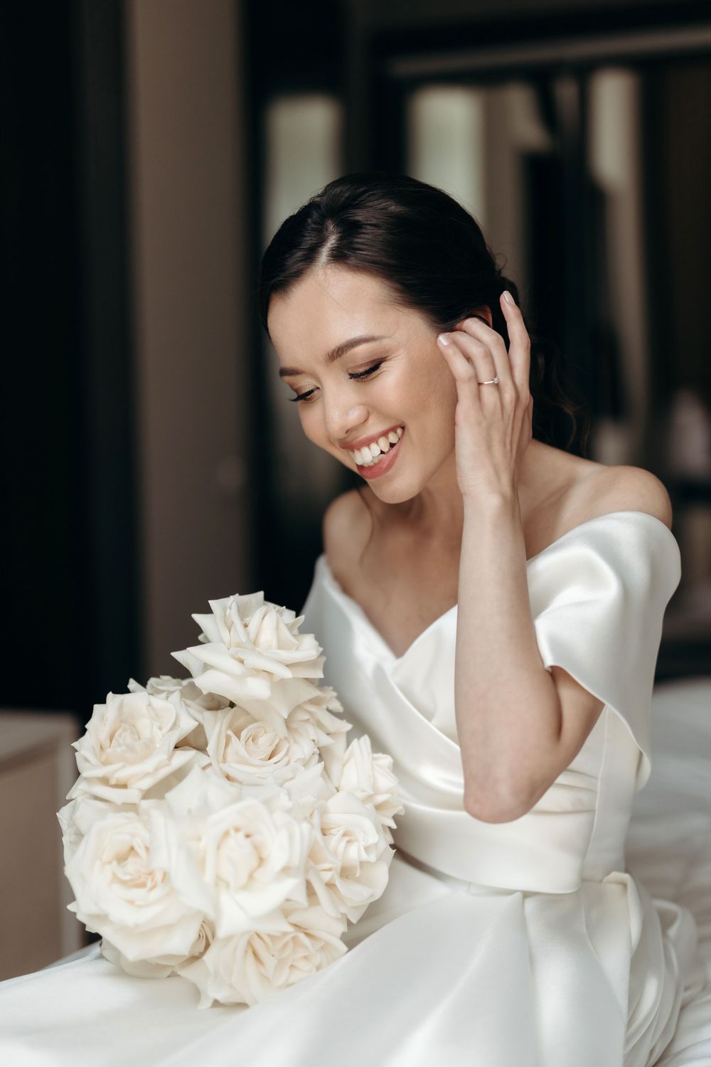 Woman in a wedding dress smiling and holding a bouquet of white flowers