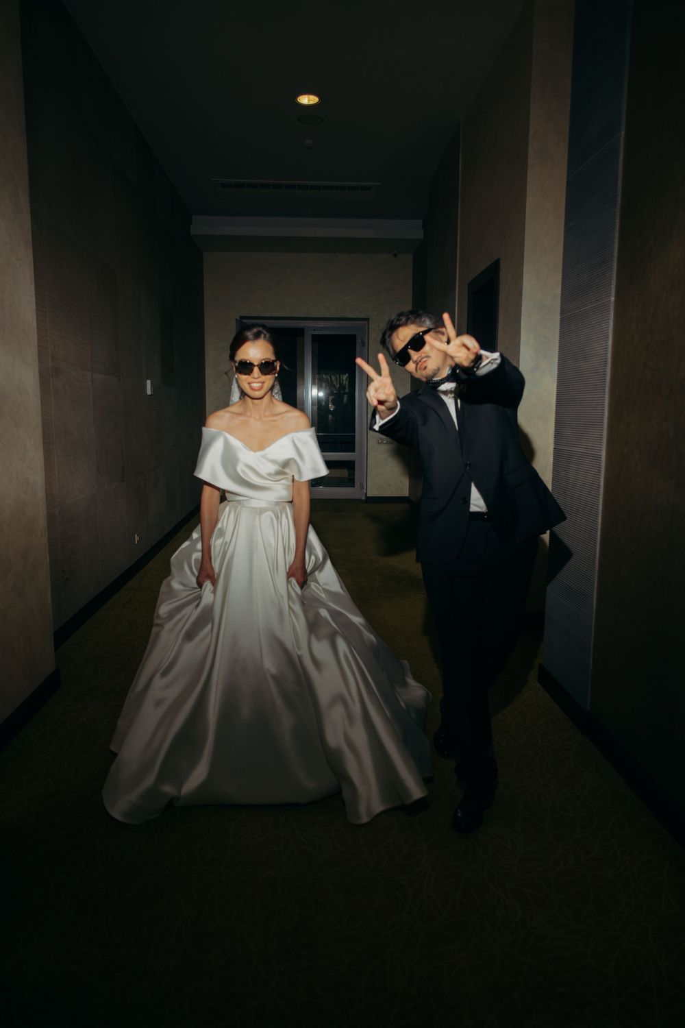 bride and groom wearing sunglasses and posing in a hotel hall