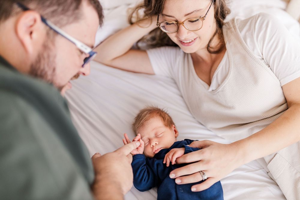 A couple looking at their newborn on a bed, capturing connection in Maputo, Mozambique, by Mercy Koimburi Photography.