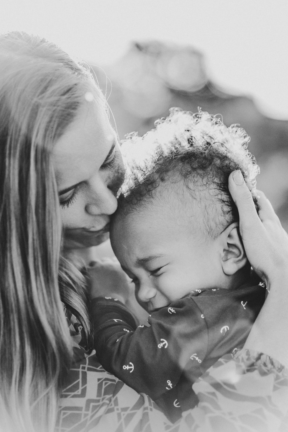 A mom kissing the top of her baby's forehead showing love and connection in Maputo, Mozambique.