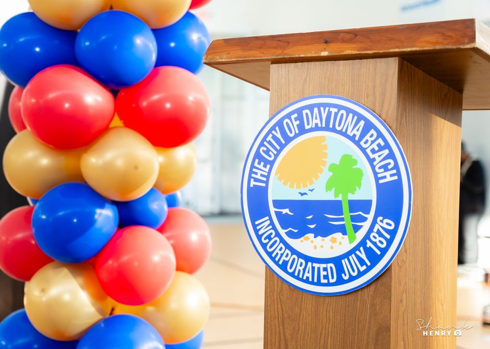 City of Daytona Beach logo podium with festive red, white and blue balloon arch decoration.