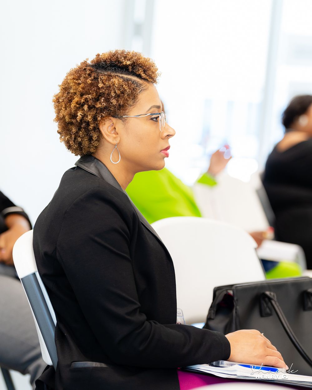 Professional in black blazer attentively listening during business meeting.