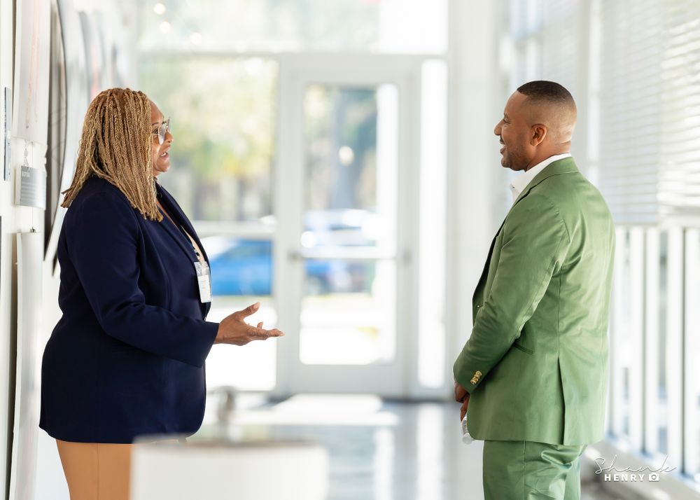 Two professionals having conversation in bright office hallway.