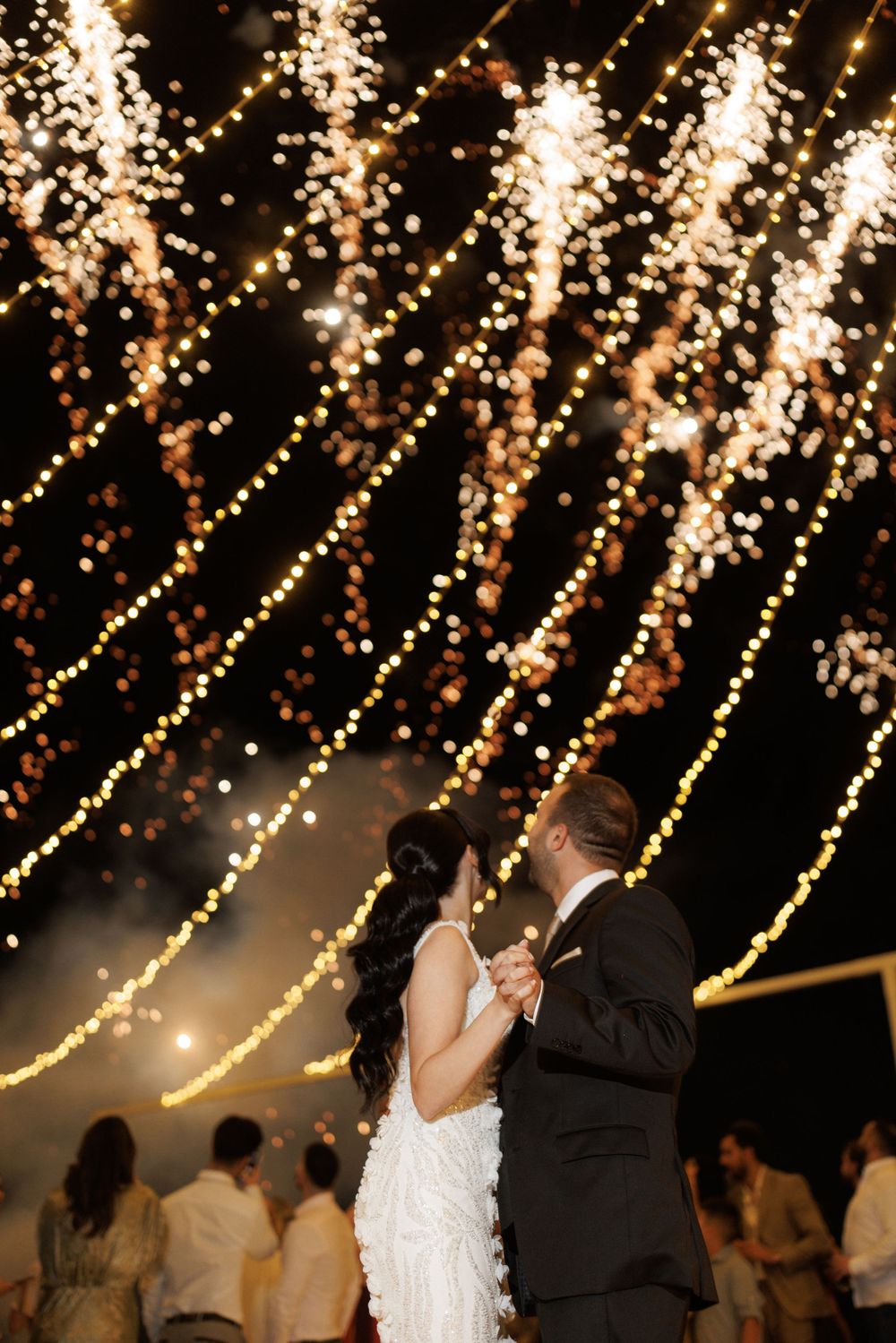 A romantic dance under twinkling string lights at a nighttime wedding reception.