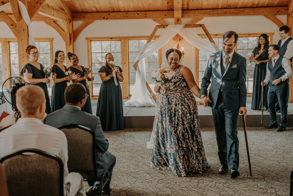 Joyful wedding moment in sunlit timber frame venue with exposed beams and natural lighting.