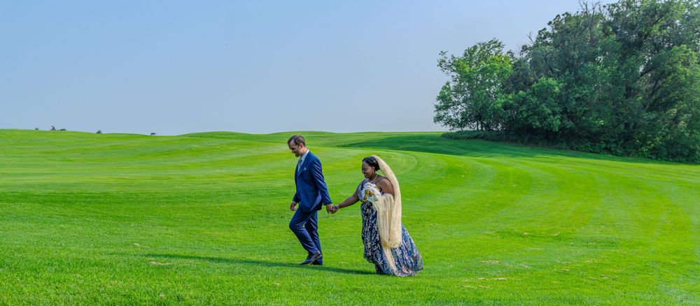 A couple walks together on a green golf course holding hands.