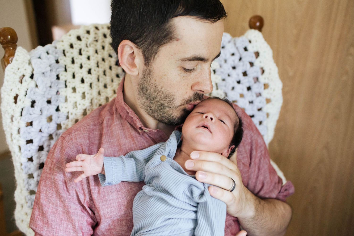 Everett newborn photographer: A dad kisses his newborn son at an in-home photo session