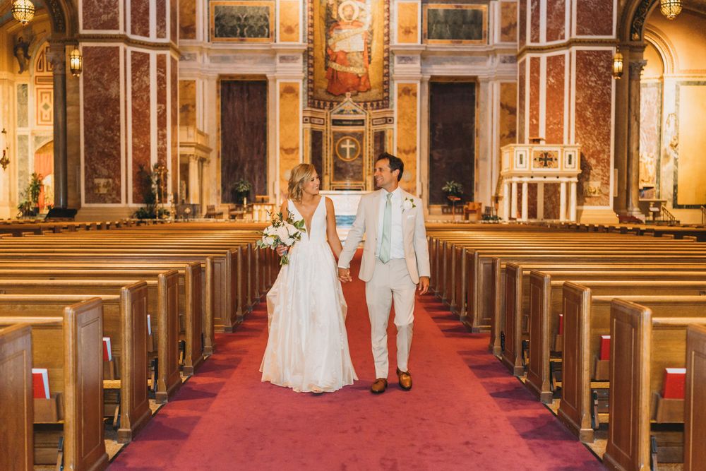 Elegant church interior with red carpet aisle and ornate decor during wedding ceremony.